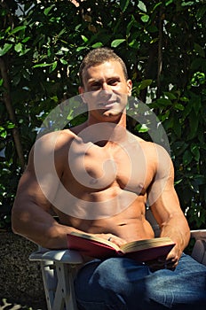 Handsome athletic young man reading book outside