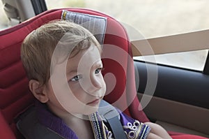 Handsome attentitive baby boy in child car seat