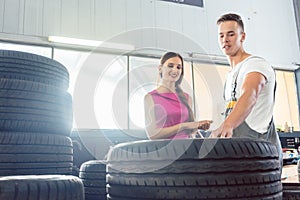 Handsome auto mechanic helping a customer to choose from various tires