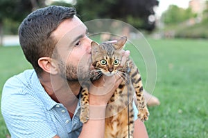 Handsome bachelor kissing his pet outdoors