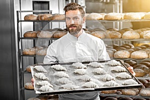 Handsome baker holding tray full of freshly baked croisants