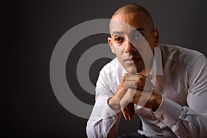 Handsome bald businessman thinking against gray background