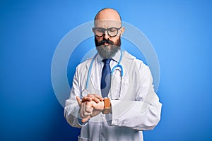 Handsome bald doctor man with beard wearing glasses and stethoscope over blue background Checking the time on wrist watch, relaxed