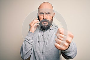 Handsome bald man with beard having conversation talking on the smartphone annoyed and frustrated shouting with anger, crazy and
