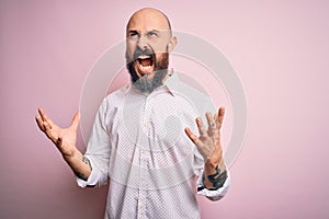 Handsome bald man with beard wearing elegant shirt over isolated pink background crazy and mad shouting and yelling with