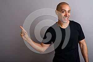 Handsome bald man smiling and showing copy space with pointing finger