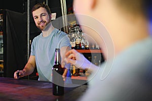 Handsome bar tender standing behind his counter in a pub