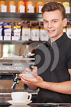 Handsome barista writing check and smiling.