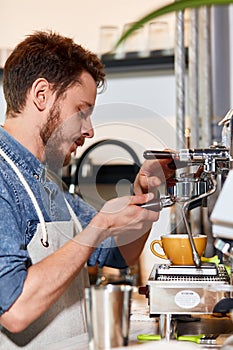 Handsome barman preparing ground coffee for customer in coffee shop.