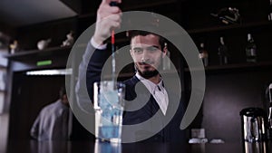 Handsome barman professional at posh bar making cocktail drinks