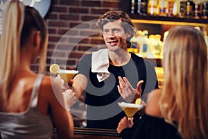 Handsome bartender serving cocktails in a pub