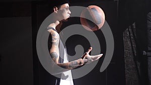 Handsome basketball player with tattoos playing with ball and waiting for game to start