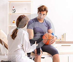 Handsome basketball player visiting female doctor traumatologist