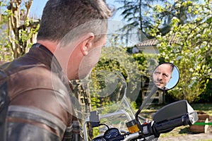 Handsome beard man in brown motorbike jacket reflexion in rear mirror on motorcycle