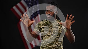 Handsome bearded African American lieutenant sergeant persuading recruits with USA flag at black background. Portrait of