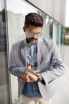 Handsome bearded businessman serious, looking his wrist watch