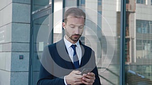 Handsome bearded businessman in using app on his mobile phone. Young man in formal suit texting messages, chatting on