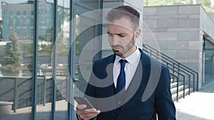 Handsome bearded businessman in using app on his mobile phone. Young man in formal suit texting messages, chatting on