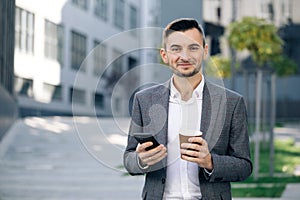 Handsome bearded businessman using mobile phone. Young man texting messages, cheating on his smartphone while walking