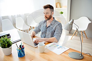 Handsome bearded concentrated businessman typing on laptop photo