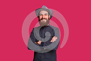 Handsome bearded cowboy with foldedhands looking at camera stand