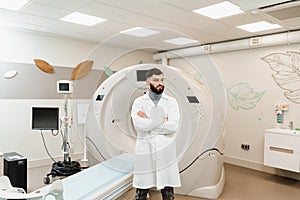 Handsome bearded doctor in medical robe with computed tomograph for obtain detailed internal images of the body of