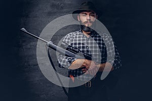 Handsome bearded hunter traveler in a fleece shirt and hat holds rifle with a sight.