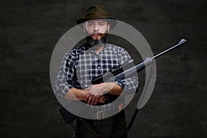 Handsome bearded hunter traveler in a fleece shirt and hat holds rifle with a sight.