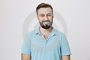 Handsome bearded man in blue t shirt on a white background. Bartender invites visitors with a wide smile on his face to