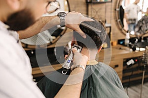 Handsome bearded man cutting hair of confident male client in berber shop