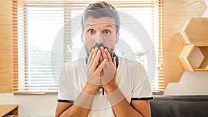 Handsome bearded man with facial expression laughing holding his hand on mouth