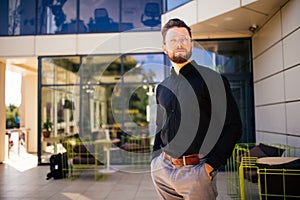 Handsome young bearded man in front of office building outdoors