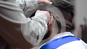 Handsome bearded man getting haircut by hairdresser at the barber shop.