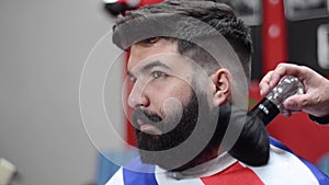 Handsome bearded man getting haircut by hairdresser at the barber shop.