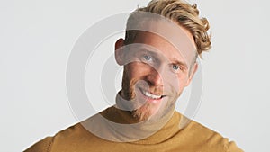 Handsome bearded man happily looking in camera over white background. Cheerful male model posing in studio