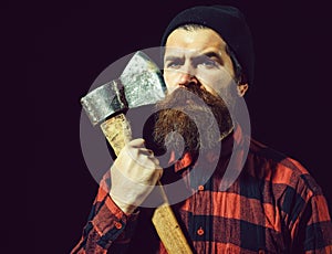 Handsome bearded man in hat holds axe on black background