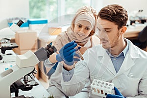 Handsome bearded man looking at the test tube with seeds