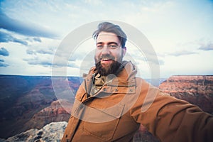 Handsome bearded man makes selfie photo on travel hiking at Grand Canyon in Arizona