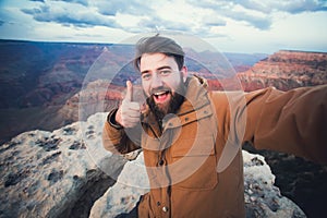 Handsome bearded man makes selfie photo on travel hiking at Grand Canyon in Arizona