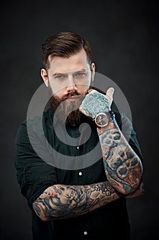 Handsome bearded man with tattoos on his hands looks at the camera with a thoughtful look