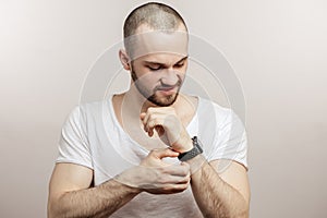 Handsome bearded man is touching his watch