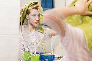 Handsome bearded man with towel, drying hair in a bathroom near mirror