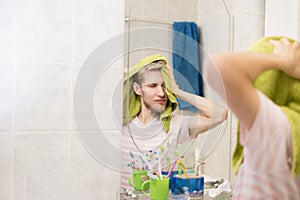 Handsome bearded man with towel, drying hair in a bathroom near mirror