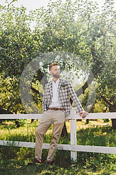 Handsome bearded man in vintage clothing. Portrait stylish groom in plaid jacket on his wedding day in the park. Rustic hipster