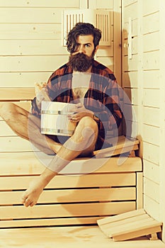 Handsome bearded man in wooden bath with bucket