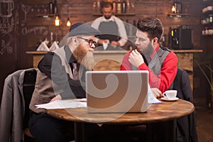 Handsome bearded men in suits talking about last moth results in a vintage pub.