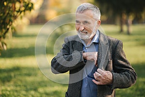 Handsome bearded old man take a smartphone from the jacket