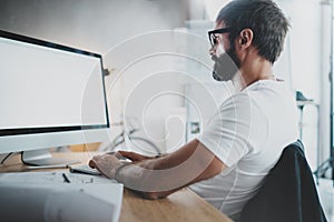 Handsome bearded professional architect wearing eye glasses working at modern loft studio-office with desktop computer photo