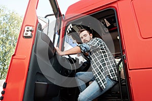 Handsome bearded truck driver inside his red cargo truck