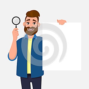 Handsome bearded young man showing/holding magnifying glass and blank/empty poster, paper or sheet in hand. Search, find.